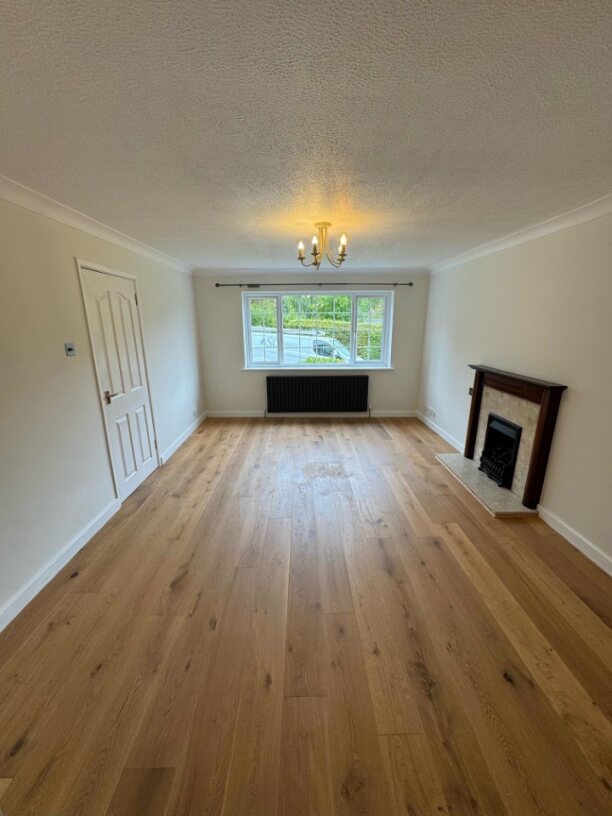 a white, empty living room with wooden flooring